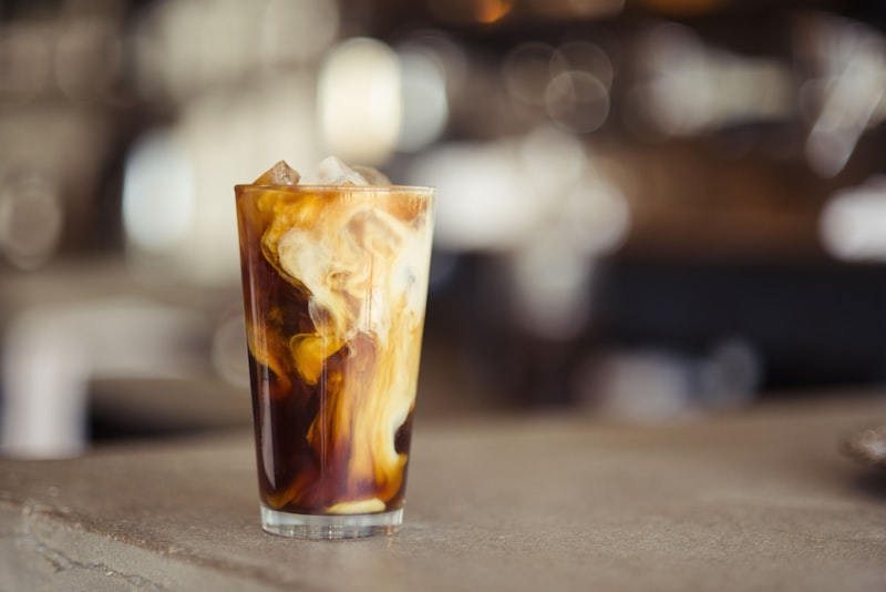 An iced cold brew with cream swirling through it