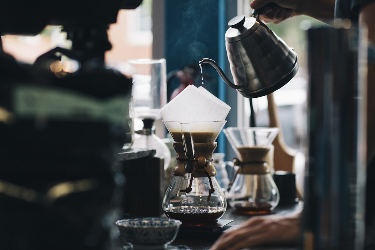 A barista pouring water from a gooseneck kettle over a Chemex brewer at SOLÉ